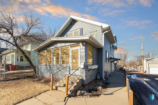 view of property exterior featuring driveway, a sunroom, and fence