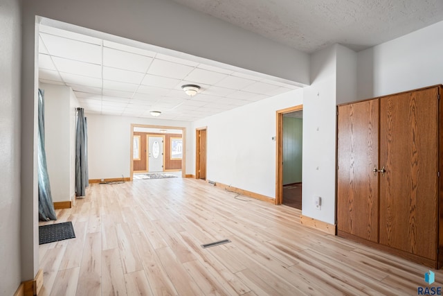 spare room with light wood-type flooring, visible vents, baseboards, and a paneled ceiling