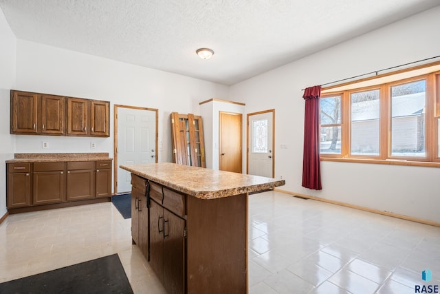 kitchen featuring a kitchen island, baseboards, light countertops, and a textured ceiling