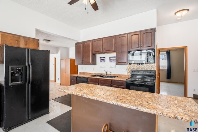 kitchen featuring a textured ceiling, ceiling fan, light stone counters, a sink, and black appliances