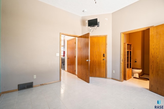 bedroom featuring ensuite bath, baseboards, and visible vents