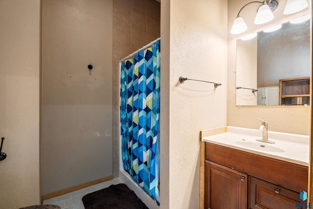 bathroom featuring curtained shower, tile patterned flooring, vanity, and baseboards