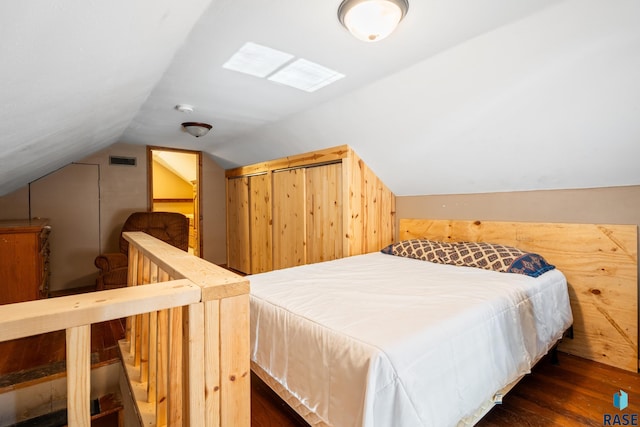 bedroom with lofted ceiling, visible vents, and wood finished floors