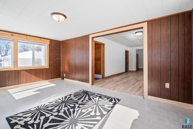 tiled empty room featuring a paneled ceiling, wood walls, and baseboards