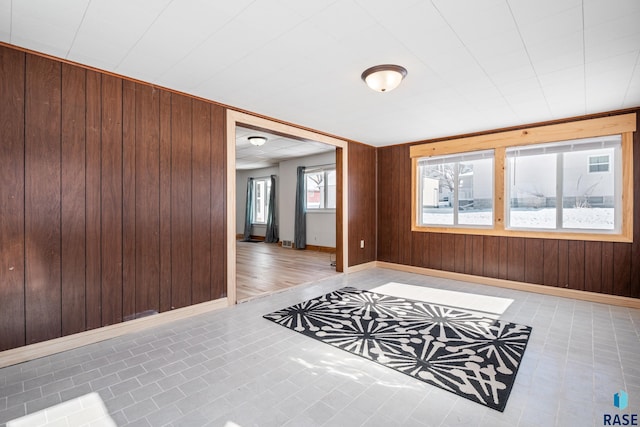 spare room featuring wood walls and baseboards