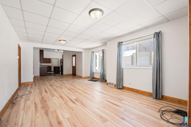 spare room featuring visible vents, a drop ceiling, light wood-style flooring, and baseboards