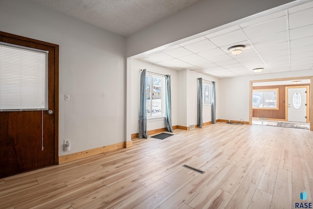 unfurnished room featuring a paneled ceiling, baseboards, visible vents, and wood finished floors