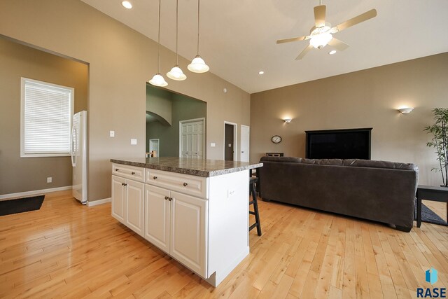 kitchen with light wood-style floors, freestanding refrigerator, white cabinetry, and a kitchen island