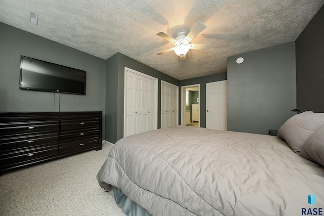 bedroom featuring multiple closets, washer / dryer, ceiling fan, and a textured ceiling