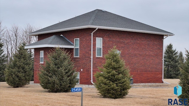 view of home's exterior with brick siding and roof with shingles