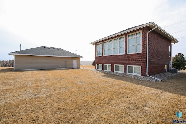 rear view of house featuring brick siding, a lawn, and central air condition unit