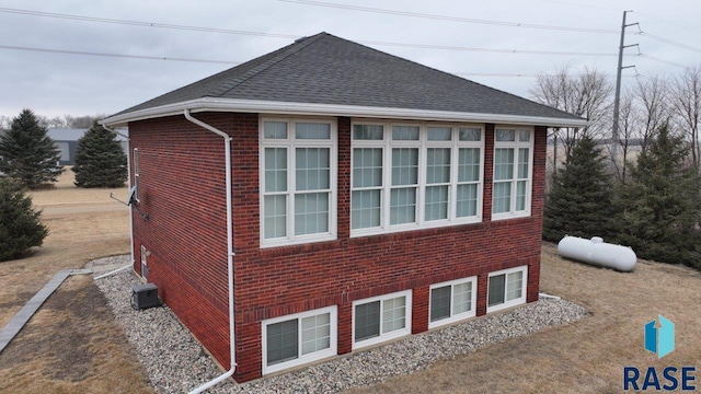 view of home's exterior featuring a shingled roof and brick siding