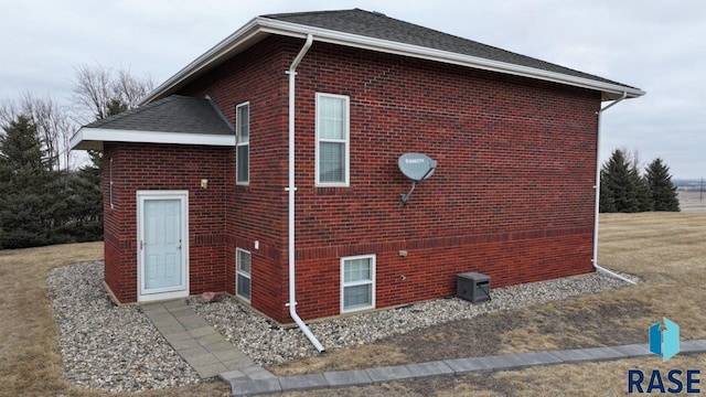 view of side of property featuring a shingled roof and brick siding