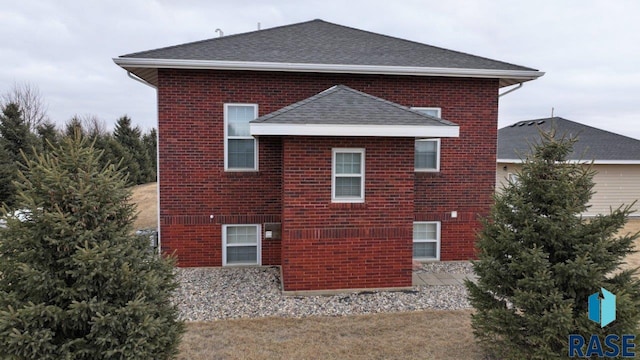 view of property exterior featuring a shingled roof and brick siding