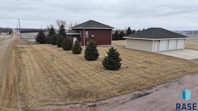 exterior space featuring a garage, an outbuilding, brick siding, and a front yard