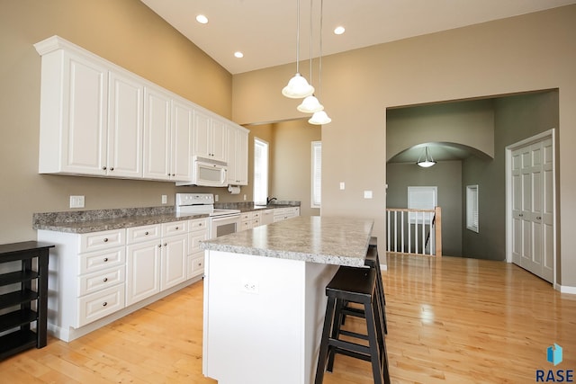 kitchen with light wood-type flooring, white appliances, white cabinets, and a kitchen island