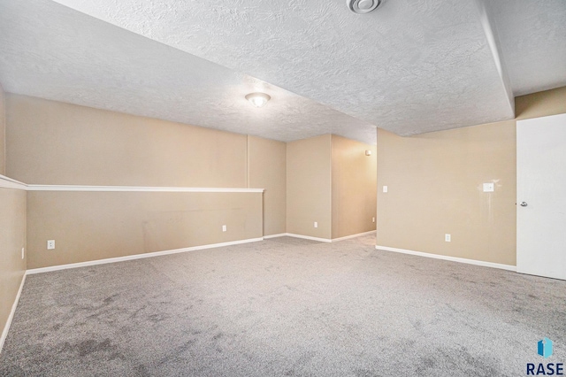 finished basement featuring carpet floors, baseboards, and a textured ceiling