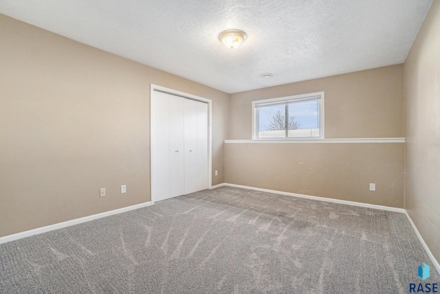 unfurnished bedroom with a textured ceiling, a closet, carpet flooring, and baseboards