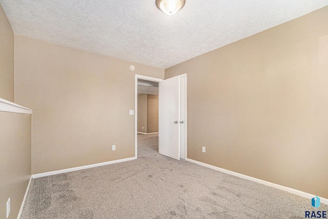 unfurnished bedroom with a textured ceiling, carpet floors, and baseboards