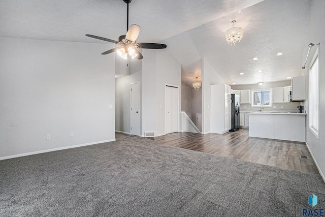 unfurnished living room featuring baseboards, visible vents, vaulted ceiling, dark colored carpet, and a sink