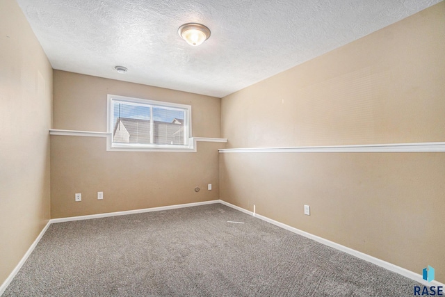 carpeted spare room with a textured ceiling and baseboards