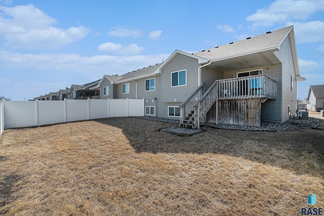 rear view of property featuring central air condition unit, stairs, fence, and a lawn