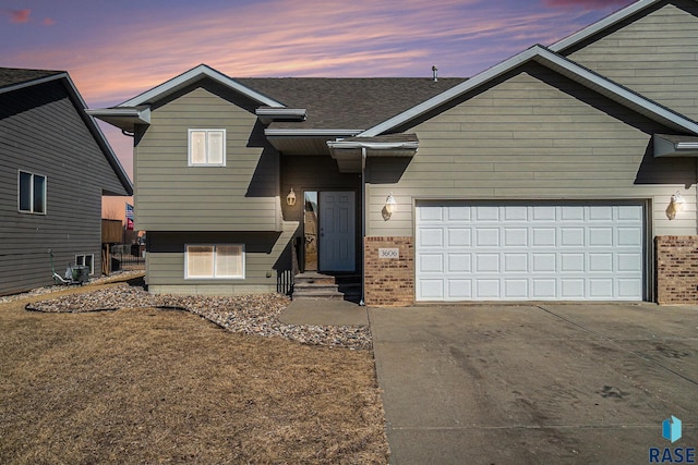 view of front of property featuring a shingled roof, brick siding, driveway, and an attached garage