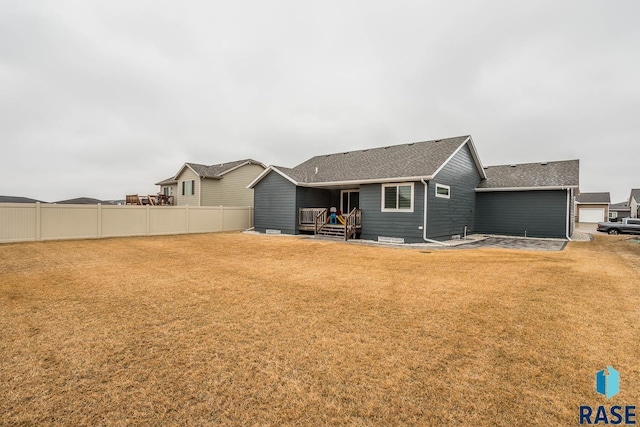 back of house featuring fence and a lawn