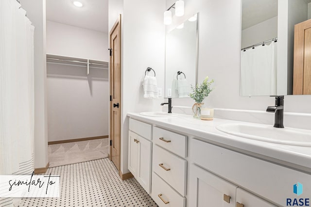 full bathroom featuring double vanity, a sink, and a walk in closet