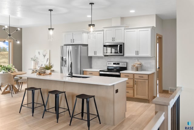 kitchen featuring appliances with stainless steel finishes, backsplash, a sink, and a breakfast bar