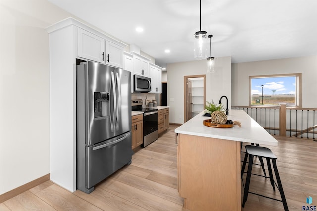 kitchen with light countertops, appliances with stainless steel finishes, white cabinetry, and light wood-style floors