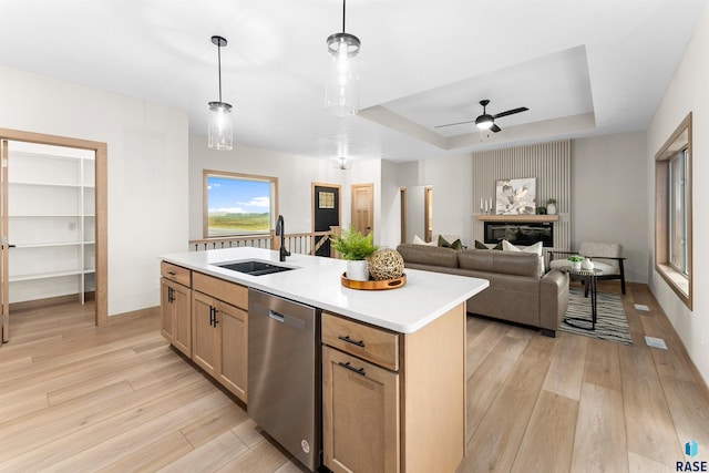 kitchen featuring light wood finished floors, a raised ceiling, dishwasher, light countertops, and a sink