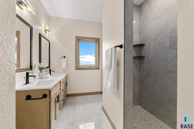 bathroom featuring marble finish floor, double vanity, a sink, a walk in shower, and baseboards