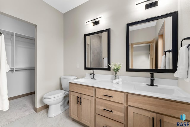 bathroom featuring marble finish floor, double vanity, a sink, and toilet