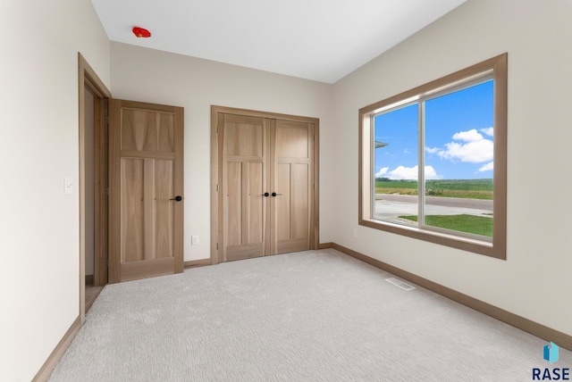 unfurnished bedroom with light carpet, baseboards, visible vents, and a closet