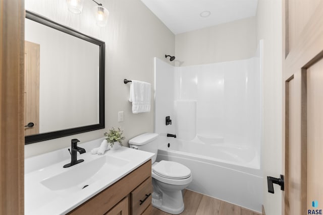 full bath with shower / bathtub combination, vanity, wood finished floors, and toilet