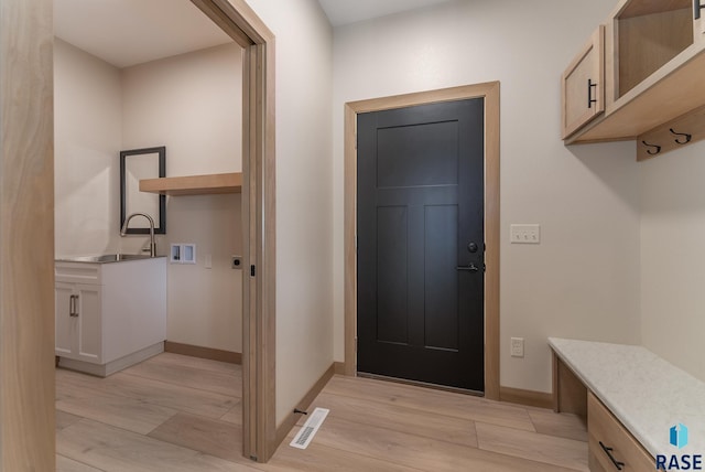 mudroom with light wood-style flooring, a sink, visible vents, and baseboards