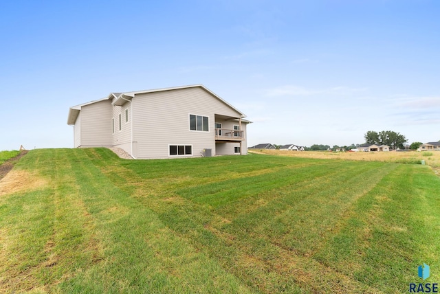 view of home's exterior featuring a balcony and a yard