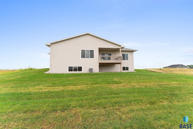 rear view of house featuring a balcony, cooling unit, and a yard