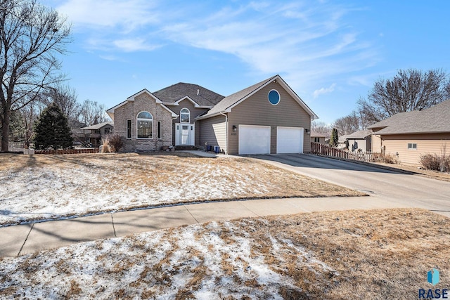 traditional-style house with a garage, concrete driveway, brick siding, and fence