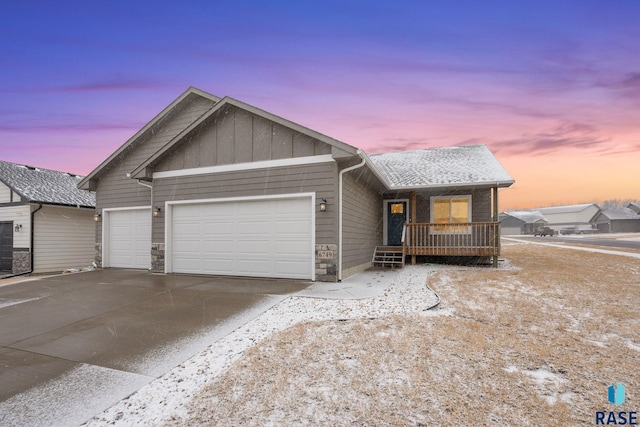 view of front of property featuring driveway, stone siding, an attached garage, a porch, and board and batten siding