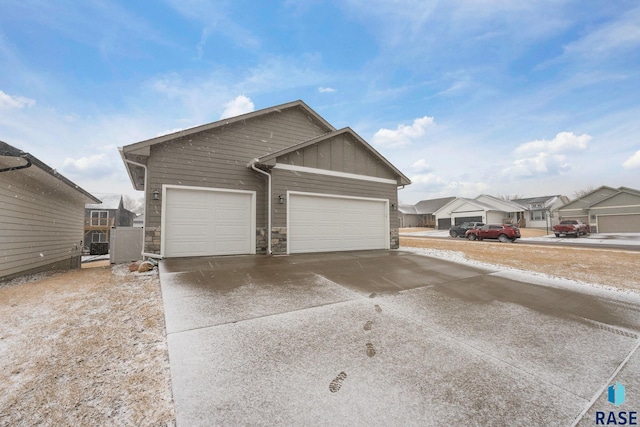 view of front of home with board and batten siding, concrete driveway, stone siding, and an attached garage