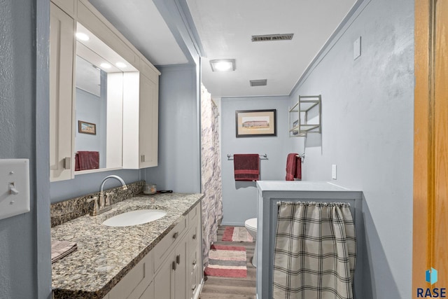 bathroom with visible vents, vanity, toilet, and wood finished floors