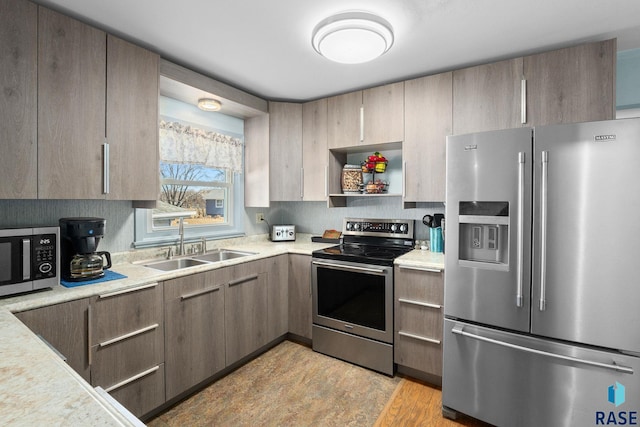 kitchen featuring stainless steel appliances, light countertops, light wood-style floors, open shelves, and a sink