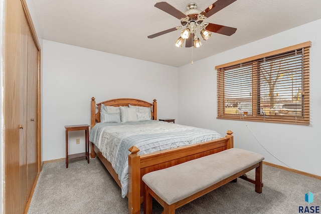 bedroom featuring ceiling fan, baseboards, a textured ceiling, and light colored carpet