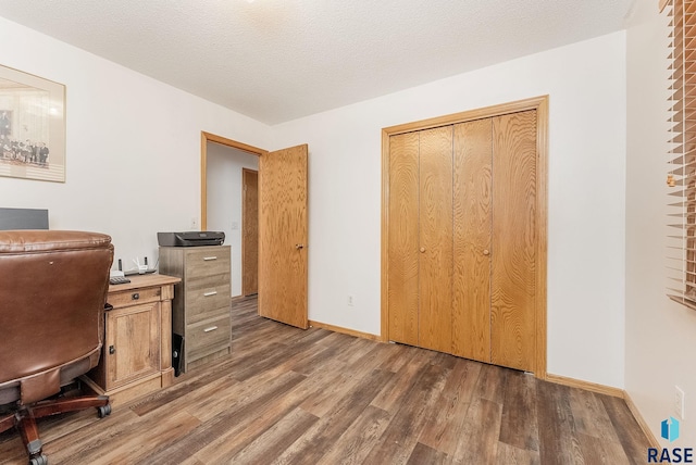 office area with a textured ceiling, baseboards, and wood finished floors