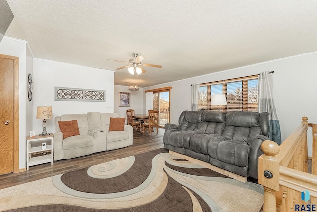 living area featuring a textured ceiling, wood finished floors, a ceiling fan, and crown molding