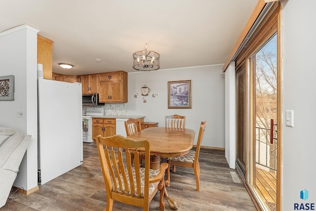 dining space featuring a notable chandelier, baseboards, and wood finished floors