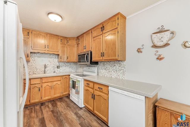 kitchen featuring white appliances, dark wood finished floors, decorative backsplash, light countertops, and a sink