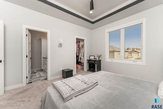 bedroom featuring a textured ceiling, carpet flooring, baseboards, a spacious closet, and a closet